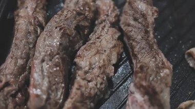 Galbi cızırdayan Kore barbekü deneyimi otantik restoran sahnesi için duman ve ızgara izleriyle dinamik pişirme hareketleri gösteriyor.
