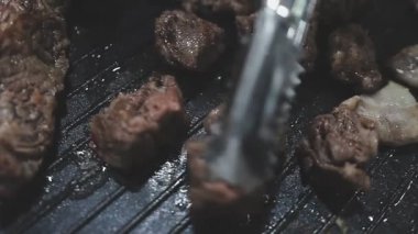 Galbi cızırdayan Kore barbekü deneyimi otantik restoran sahnesi için duman ve ızgara izleriyle dinamik pişirme hareketleri gösteriyor.