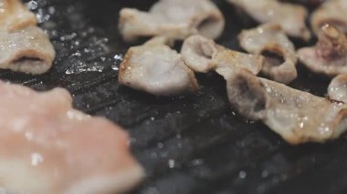 Galbi cızırdayan Kore barbekü deneyimi otantik restoran sahnesi için duman ve ızgara izleriyle dinamik pişirme hareketleri gösteriyor.