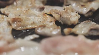 Galbi cızırdayan Kore barbekü deneyimi otantik restoran sahnesi için duman ve ızgara izleriyle dinamik pişirme hareketleri gösteriyor.