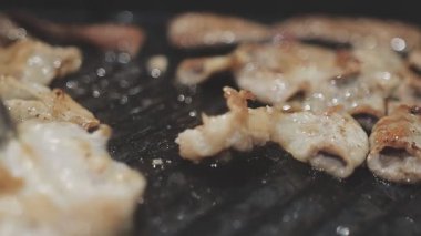 Galbi cızırdayan Kore barbekü deneyimi otantik restoran sahnesi için duman ve ızgara izleriyle dinamik pişirme hareketleri gösteriyor.