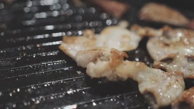 Galbi cızırdayan Kore barbekü deneyimi otantik restoran sahnesi için duman ve ızgara izleriyle dinamik pişirme hareketleri gösteriyor.