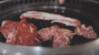Galbi cızırdayan Kore barbekü deneyimi otantik restoran sahnesi için duman ve ızgara izleriyle dinamik pişirme hareketleri gösteriyor.