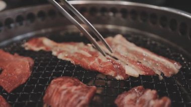 Galbi cızırdayan Kore barbekü deneyimi otantik restoran sahnesi için duman ve ızgara izleriyle dinamik pişirme hareketleri gösteriyor.