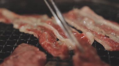 Galbi cızırdayan Kore barbekü deneyimi otantik restoran sahnesi için duman ve ızgara izleriyle dinamik pişirme hareketleri gösteriyor.