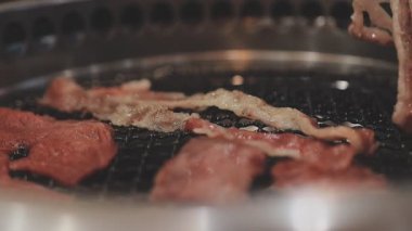 Galbi cızırdayan Kore barbekü deneyimi otantik restoran sahnesi için duman ve ızgara izleriyle dinamik pişirme hareketleri gösteriyor.