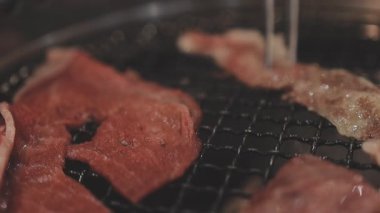 Galbi cızırdayan Kore barbekü deneyimi otantik restoran sahnesi için duman ve ızgara izleriyle dinamik pişirme hareketleri gösteriyor.