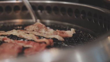 Galbi cızırdayan Kore barbekü deneyimi otantik restoran sahnesi için duman ve ızgara izleriyle dinamik pişirme hareketleri gösteriyor.