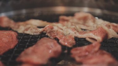 Galbi cızırdayan Kore barbekü deneyimi otantik restoran sahnesi için duman ve ızgara izleriyle dinamik pişirme hareketleri gösteriyor.