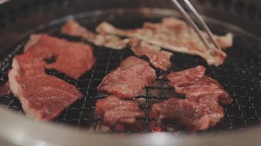 Galbi cızırdayan Kore barbekü deneyimi otantik restoran sahnesi için duman ve ızgara izleriyle dinamik pişirme hareketleri gösteriyor.