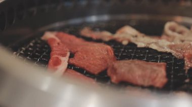 Galbi cızırdayan Kore barbekü deneyimi otantik restoran sahnesi için duman ve ızgara izleriyle dinamik pişirme hareketleri gösteriyor.