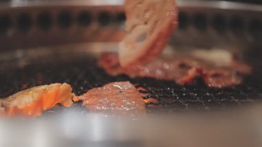 Galbi cızırdayan Kore barbekü deneyimi otantik restoran sahnesi için duman ve ızgara izleriyle dinamik pişirme hareketleri gösteriyor.