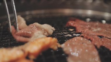 Galbi cızırdayan Kore barbekü deneyimi otantik restoran sahnesi için duman ve ızgara izleriyle dinamik pişirme hareketleri gösteriyor.