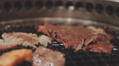 Galbi cızırdayan Kore barbekü deneyimi otantik restoran sahnesi için duman ve ızgara izleriyle dinamik pişirme hareketleri gösteriyor.