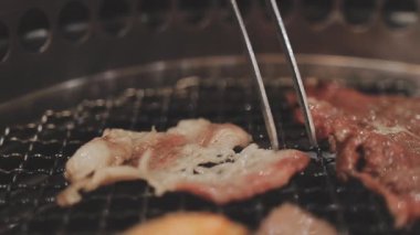 Galbi cızırdayan Kore barbekü deneyimi otantik restoran sahnesi için duman ve ızgara izleriyle dinamik pişirme hareketleri gösteriyor.