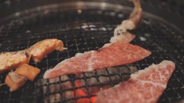 Galbi cızırdayan Kore barbekü deneyimi otantik restoran sahnesi için duman ve ızgara izleriyle dinamik pişirme hareketleri gösteriyor.