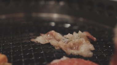 Galbi cızırdayan Kore barbekü deneyimi otantik restoran sahnesi için duman ve ızgara izleriyle dinamik pişirme hareketleri gösteriyor.