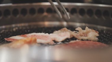 Galbi cızırdayan Kore barbekü deneyimi otantik restoran sahnesi için duman ve ızgara izleriyle dinamik pişirme hareketleri gösteriyor.