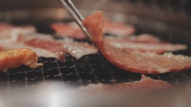 Galbi cızırdayan Kore barbekü deneyimi otantik restoran sahnesi için duman ve ızgara izleriyle dinamik pişirme hareketleri gösteriyor.