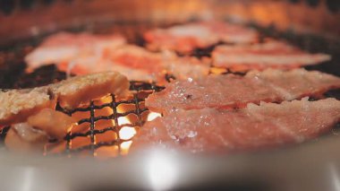 Galbi cızırdayan Kore barbekü deneyimi otantik restoran sahnesi için duman ve ızgara izleriyle dinamik pişirme hareketleri gösteriyor.