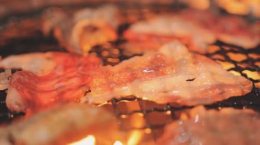 Galbi cızırdayan Kore barbekü deneyimi otantik restoran sahnesi için duman ve ızgara izleriyle dinamik pişirme hareketleri gösteriyor.