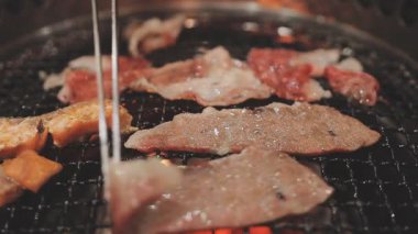 Galbi cızırdayan Kore barbekü deneyimi otantik restoran sahnesi için duman ve ızgara izleriyle dinamik pişirme hareketleri gösteriyor.