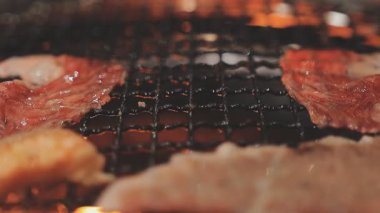 Galbi cızırdayan Kore barbekü deneyimi otantik restoran sahnesi için duman ve ızgara izleriyle dinamik pişirme hareketleri gösteriyor.