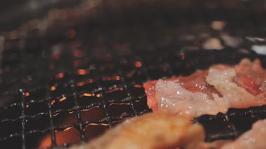 Galbi cızırdayan Kore barbekü deneyimi otantik restoran sahnesi için duman ve ızgara izleriyle dinamik pişirme hareketleri gösteriyor.