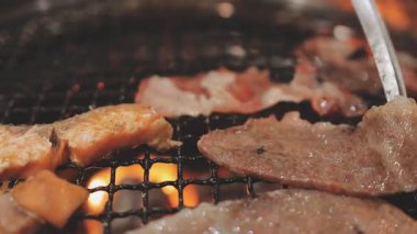 Galbi cızırdayan Kore barbekü deneyimi otantik restoran sahnesi için duman ve ızgara izleriyle dinamik pişirme hareketleri gösteriyor.