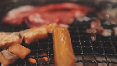 Galbi cızırdayan Kore barbekü deneyimi otantik restoran sahnesi için duman ve ızgara izleriyle dinamik pişirme hareketleri gösteriyor.