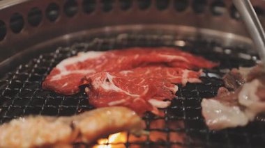 Galbi cızırdayan Kore barbekü deneyimi otantik restoran sahnesi için duman ve ızgara izleriyle dinamik pişirme hareketleri gösteriyor.