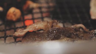Galbi cızırdayan Kore barbekü deneyimi otantik restoran sahnesi için duman ve ızgara izleriyle dinamik pişirme hareketleri gösteriyor.