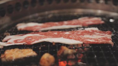 Galbi cızırdayan Kore barbekü deneyimi otantik restoran sahnesi için duman ve ızgara izleriyle dinamik pişirme hareketleri gösteriyor.