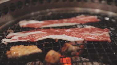 Galbi cızırdayan Kore barbekü deneyimi otantik restoran sahnesi için duman ve ızgara izleriyle dinamik pişirme hareketleri gösteriyor.