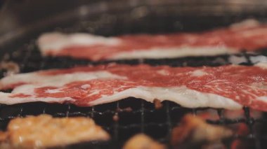 Galbi cızırdayan Kore barbekü deneyimi otantik restoran sahnesi için duman ve ızgara izleriyle dinamik pişirme hareketleri gösteriyor.