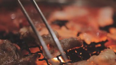 Galbi cızırdayan Kore barbekü deneyimi otantik restoran sahnesi için duman ve ızgara izleriyle dinamik pişirme hareketleri gösteriyor.