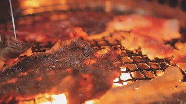 Galbi cızırdayan Kore barbekü deneyimi otantik restoran sahnesi için duman ve ızgara izleriyle dinamik pişirme hareketleri gösteriyor.