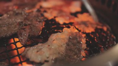 Galbi cızırdayan Kore barbekü deneyimi otantik restoran sahnesi için duman ve ızgara izleriyle dinamik pişirme hareketleri gösteriyor.