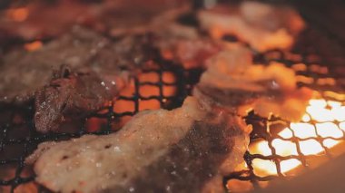 Galbi cızırdayan Kore barbekü deneyimi otantik restoran sahnesi için duman ve ızgara izleriyle dinamik pişirme hareketleri gösteriyor.