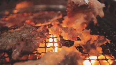 Galbi cızırdayan Kore barbekü deneyimi otantik restoran sahnesi için duman ve ızgara izleriyle dinamik pişirme hareketleri gösteriyor.