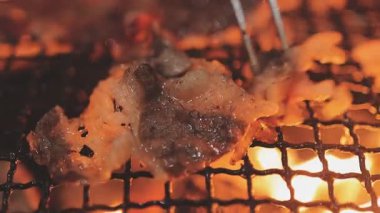 Galbi cızırdayan Kore barbekü deneyimi otantik restoran sahnesi için duman ve ızgara izleriyle dinamik pişirme hareketleri gösteriyor.