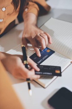 Çevrimiçi ödeme, kredi kartı tutan ve online alışveriş için akıllı telefon kullanan kadının elleri.