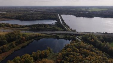 Renkli sonbahar ağaçlarıyla çevrili sakin gölleri gösteren güzel bir hava manzarası keşfedin. Huzurlu manzara doğayı, canlı paletleri ve sakin suları yakalar..