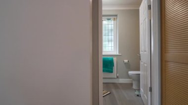 Açık renkli ve havluyla birlikte tuvaletin de görülebildiği bir banyo manzarası. Mekan bakımlı ve düzenli görünüyor..