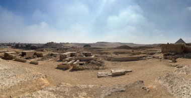 Kahire, Mısır - 01: 15 2025: Mısır 'daki Giza platosunun panoramik görüntüsü, parçalı bulutlu bir gökyüzü altında antik kalıntıları ve piramitleri sergiliyor.