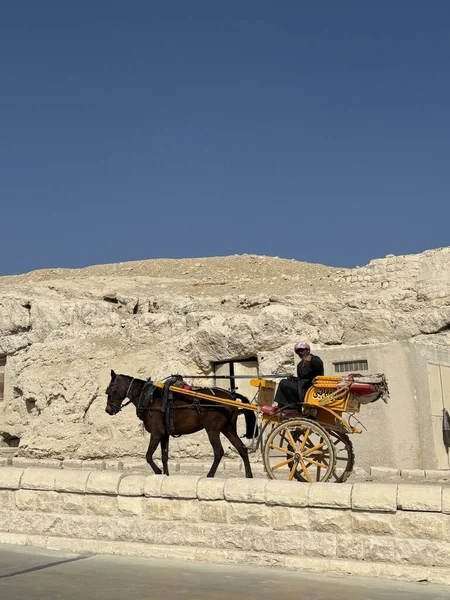 Kahire, Mısır - 01: 15 2025: Açık mavi gökyüzünün altında kumlu bir tepenin yakınındaki bir sokakta at arabası.