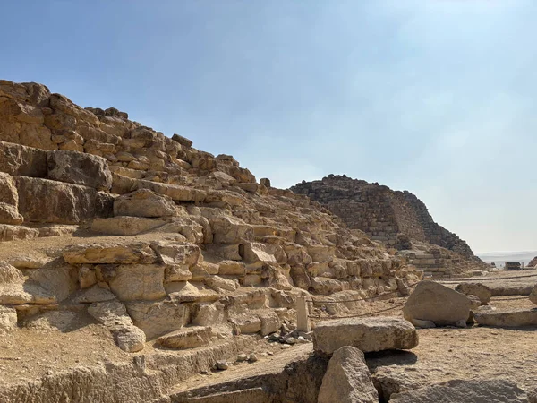 Kısmen mahvolmuş bir piramidin yakın çekimi. Taş bloklar yıpranmış ve açık mavi bir gökyüzünün altında açıkta kalmış..