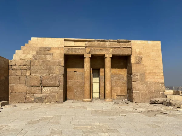 Kahire, Mısır - 01: 15 2025: Parlak mavi gökyüzünün altında sütunları olan antik taş yapı. Eski bir tapınak ya da yıkıntı gibi görünüyor..