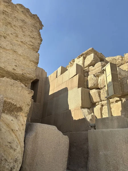 Açık mavi bir gökyüzünün altında muhtemelen antik bir yapının parçası olan eski taş bloklara yakın çekim. Sıcak, güneşli aydınlatma.