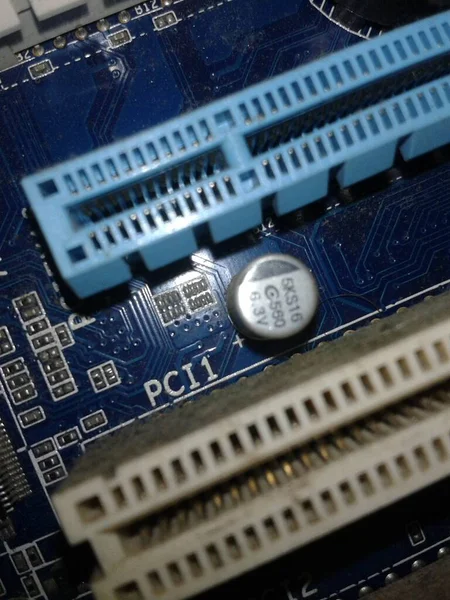 Elektronik bileşenleri ve devreleri gösteren beyaz ve mavi yuvalı mavi bir anakart..